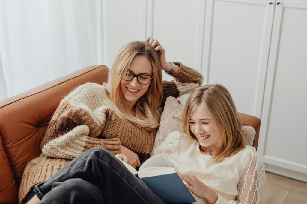 friends sharing a book on a couch